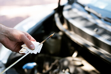 Man checking th engine oil level  at the parking. Regular car service.