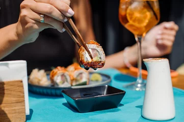 Foto op Plexiglas Customer of the restaurant is eating a sushi rolls. Close up © rostyslav84