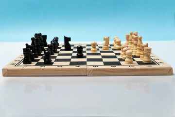 Front view of wooden chess board and chees pieces set to play. Mirror image of the game underneath...