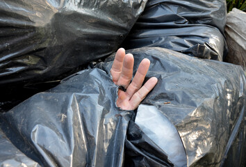 dead man in a black plastic garbage bag. bags for the dead from which a man's hand peeks out....