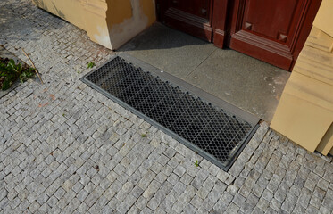 metal grating at the entrance to the building. is embedded below the surface. paving marble cubes....