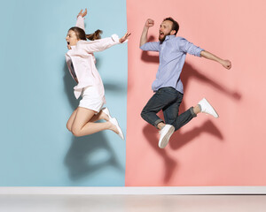 Young couple, emotional man and pretty woman messing about isolated over blue and pink background....