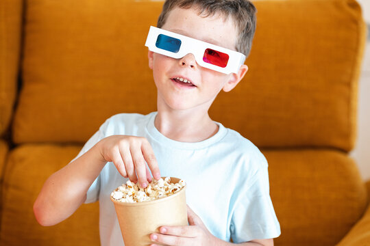 Boy in 3D glasses eating popcorn while watching movie