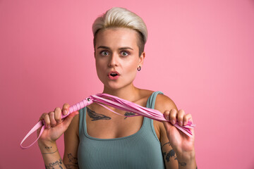 Surprised blonde woman posing with pink whip while enjoying of physical restrains during sex
