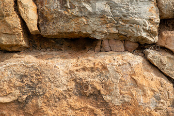 Close-up texture photo of a rough mountain rocks with cracks and pebbles.