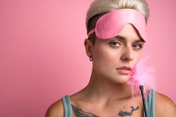 Sensual tattooed woman wearing sleep mask touching her chick with erotic feather