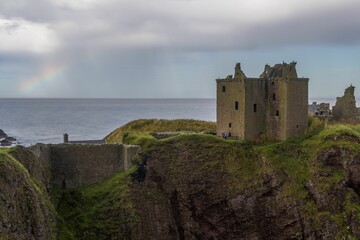 Old fortress of Dunbar Castle on the seaside cliff with rainbow over it, Scotland, Great Britain - Powered by Adobe