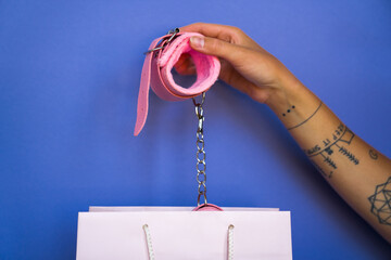Close up view of hand of tattooed girl holding handcuffs under the paper bag