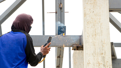 Welders work on roof trusses without safety equipment, safety concept.