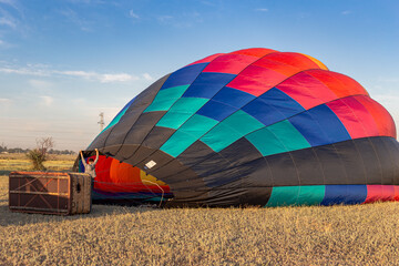 two men prepare a balloon for flight, a basket on its side for flight