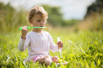 Beautiful little girl, has happy fun cheerful smiling face, soap bubble blower.