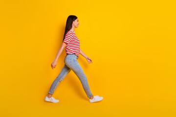 Fototapeta na wymiar Full length profile portrait of pretty cheerful person walking look empty space isolated on yellow color background