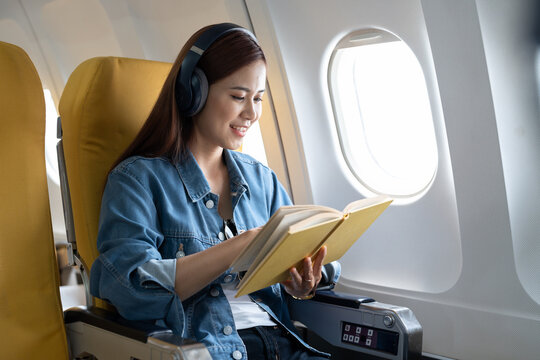 Beautiful asian travel woman reading a book in airplane