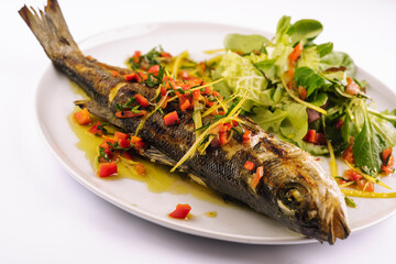 Grilled fish with vegetables on white plate