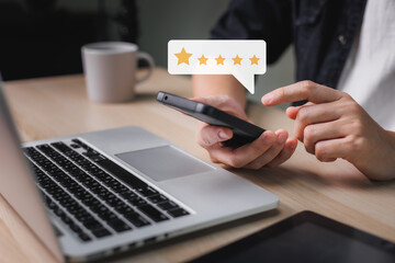 Man hand using smartphone with popup five star icon for feedback review satisfaction service at the working on table, Customer service experience, and business satisfaction survey.