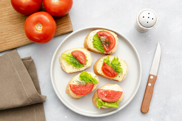 Bruschetta sandwich bread toast with soft white cheese ricotta,fresh tomatoes,basil greenery on a wooden cutting board.Tasty healthy vegetarian food,Italian cuisine appetizer. top view flat lay