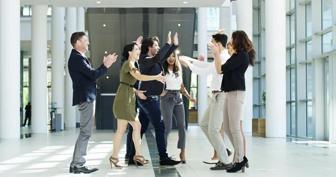 High five, jumping and celebrating with a group or team of colleagues and coworkers happy about success at work. Young and diverse business people cheering teamwork, unity and working together