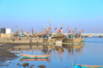 Fototapeta premium boats, empty tables and quaint buildings along the promenade at Fisherman's Village on a sunny day in india