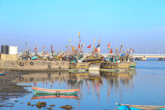 boats, empty tables and quaint buildings along the promenade at Fisherman's Village on a sunny day in india