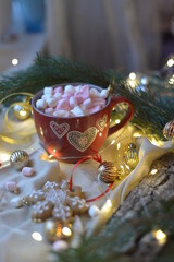 Christmas cup of hot chocolate with marshmallows surrounded by Christmas tree lights gingerbread