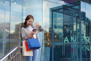 Fototapeta premium Smiling Asian woman with colored shopping bags on shopping mall background and looking happy Smiling shopping while standing in front of a department store lifestyle concept