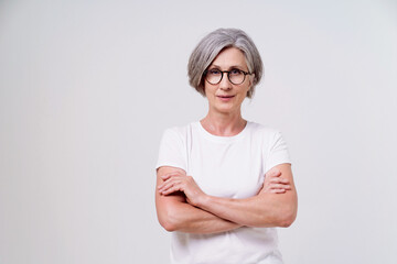 Beautiful mature grey haired woman, serious businesswoman with folded hands looking straight in...