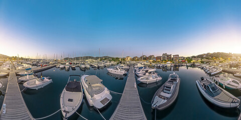Fototapeta na wymiar Aerial panorama of Porto Vecchio city harbor at night in Corsica island of France. Drone view of downtown skyline with boats and yachts in port in the Mediterranean sea after sunset. 360 degrees VR.