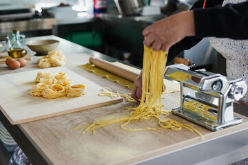 Mature woman working inside pasta factory - Focus on the fresh made pasta