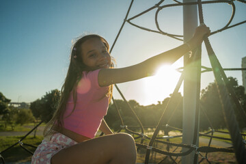 Adorable child girl climbing at the playground while having fun alone