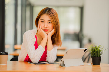 Obraz premium Happy Asian female student wearing headphones, studying online, watching webinars, podcasts on tablets, listening, learning, education courses. online meeting