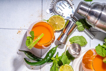 Carrot Ginger Margarita cocktail with lime, mint and hot chili pepper, original vegetable spicy drink on white tiled background copy space