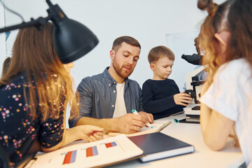 Working with the microscope. Group of children students in class at school with teacher