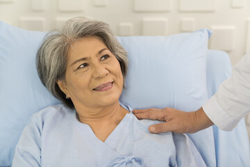 Fototapeta premium Closeup of hands of doctor and patient elderly woman. Hands of doctor touch on shoulder of elderly asian woman on bed at the hospital. People and health care concept