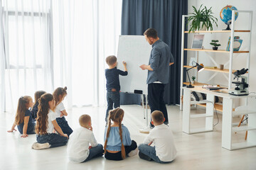 Fototapeta premium Using whiteboard. Group of children students in class at school with teacher