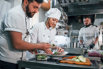 Team making salad. Professional chef preparing food in the kitchen
