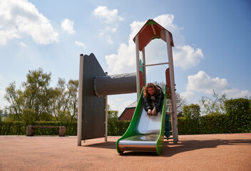 A cheerful young Caucasian man on kids slides in the playground