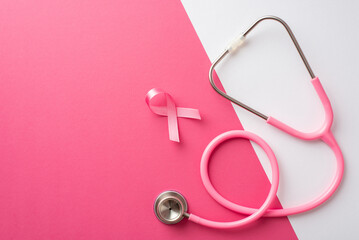 Top view photo of pink ribbon symbol of breast cancer awareness and stethoscope on bicolor pink and...