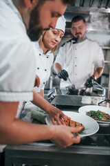 Three people woring together. Professional chef preparing food in the kitchen