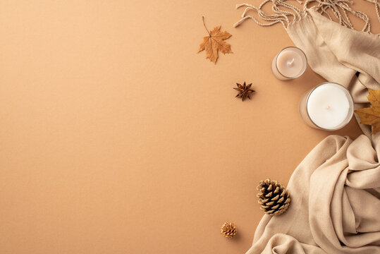 Autumn mood concept. Top view photo of candles anise yellow maple leaves pine cones and plaid on isolated beige background with copyspace