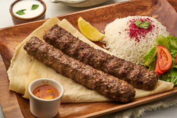 Chelo Kebab with rice, lime, salad, tomato, raita and sauce served in a dish isolated on grey background side view of fastfood