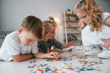 Playing puzzle game. Group of children is together at home at daytime
