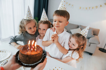 Celebrating birthday. Woman holding cake. Group of children is together at home at daytime