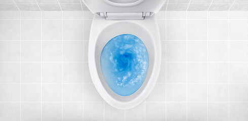 Top view of toilet bowl, blue detergent flushing in it