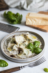 Spinach-stuffed ravioli garnished with balsamic sauce, grated parmesan and young basil leaves. Restaurant serving.