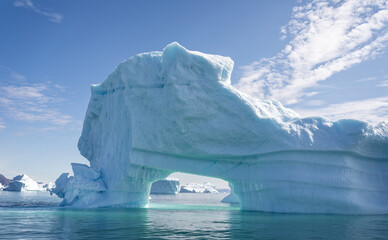 Massive iceberg with arch and beautiful aquamarine coloured ice and sea in Disko Bay, Greenland