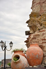 Antique vintage large amphorae near an old ruined wall