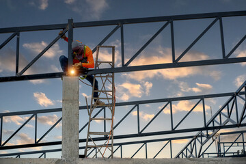 Fototapeta premium Welders wear safety belts and plastic helmets to weld steel structures.