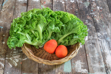 Healthy food salad lettuce and tomato in basket on wood background.
