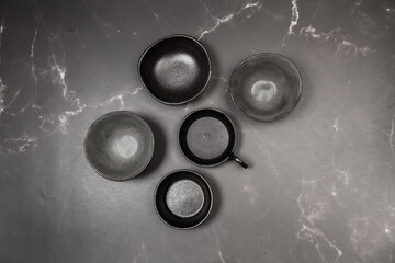 Cuencos de cerámica negros sobre un fondo de mármol negro con textura. Vista superior y de cerca....