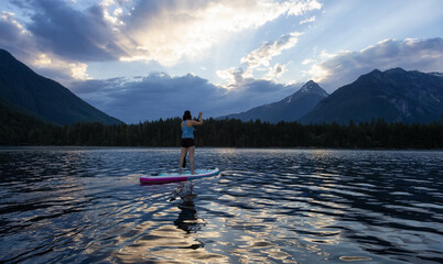 Adventurous Woman Paddle Boarding in a Lake around Canadian Mountain Landscape. Chilliwack Lake, British Columbia, Canada. Adventure Sport Travel